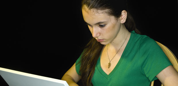 A teenage girl uses her laptop; she is very focused.